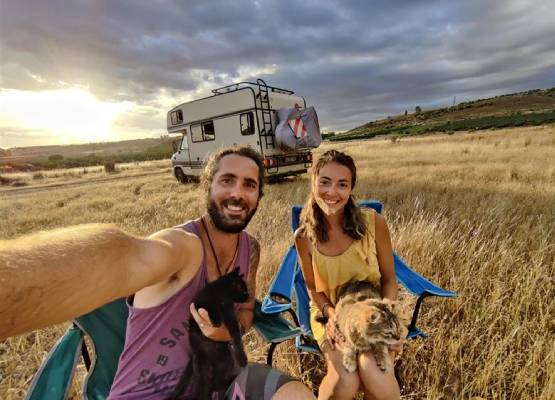 un couple et leur chat dans un champ ave un van