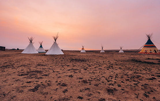 Des tentes plantées face à un coucher de soleil